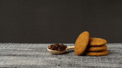 oatmeal cookies and wooden spoon with coffee beans on black background