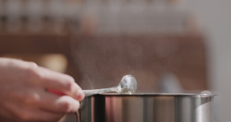 man hand stir fettuccine pasta in saucepan with boiling water closeup