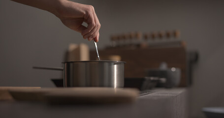 man hand stir fettuccine pasta in saucepan with boiling water closeup