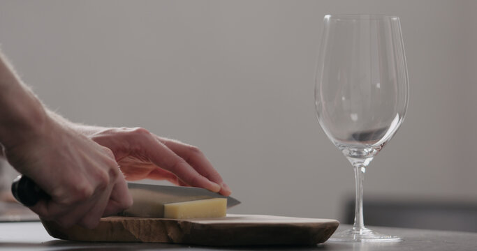 man hands cutting vintage cheese on oliveboard with wine glass