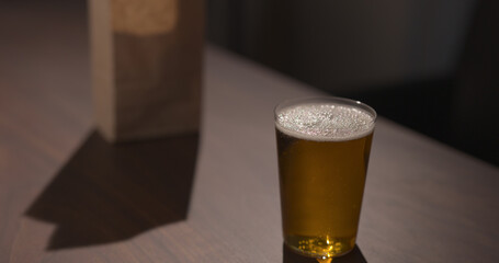 amber color fizzy drink in tumbler glass with bag of potato chips on background