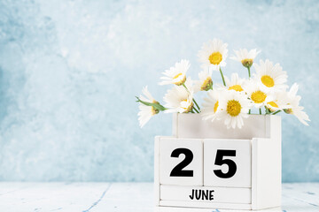 cube calendar for June with daisy flowers over blue