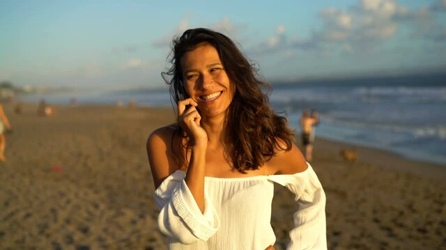 Happy beautiful woman talking on cellphone on the beach
