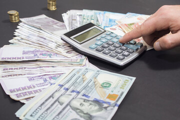counts money on a calculator, coins and paper