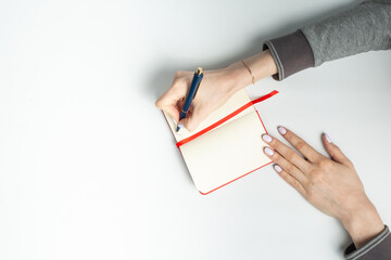 Close up of woman hand writing in notepad placed on a white background. National Handwriting Day