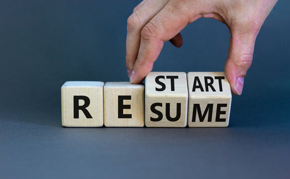 Restart and resume symbol. Businessman turns cubes and changes the word 'restart' to 'resume'. Beautiful grey background. Business and restart - resume concept. Copy space.