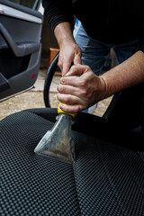 man holding a machine for cleaning. Man cleaning car seat