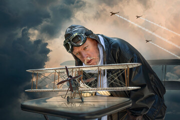 Man in pilot outfit looking at the model airplane