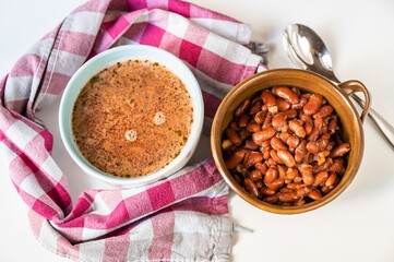 Bean soup in two bowls, towel and soup on white.