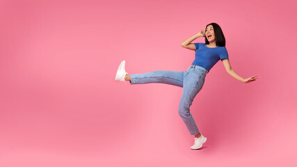 Fototapeta na wymiar Happy young asian woman jumping at pink studio, copy space