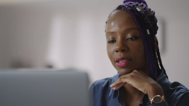 young black woman is communicating by online video call in laptop, female consultant of tech support, looking at web camera and chatting
