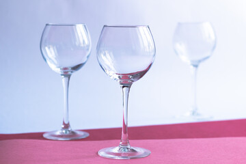 Empty wine glasses on white, rose, red paper background
