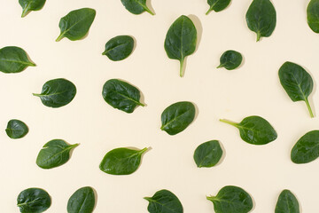 Pattern of fresh baby spinach leaves on yellow background, vegetarian food.