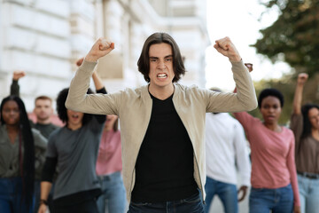 Male activist leading multiracial group of people protesting against lockdown