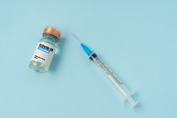 A bottle of vaccine and syringe on blue background. Covid-19 or Coronavirus Concept. Copy space.