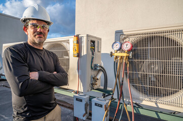 HVAC mechanic standing next to mini-split air conditioners with tools on it