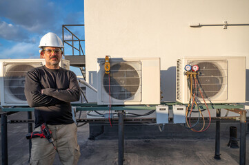 HVAC technician standing next to air conditioners outside