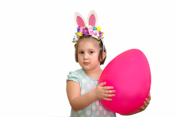 Obraz na płótnie Canvas Little cute funny girl in a hoop with Easter bunny ears and flowers is holding a huge pink Easter egg. Surprised face. On a white background. Copy space, easter poster, banner