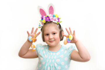 Little girl in a hoop with Easter bunny ears and flowers holds decorative Easter eggs and a bunny on a white background.Happy Easter, banner, postcard, copy space. Selective focus 