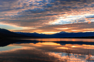 Atardecer en el lago con las montañas nevadas al fondo