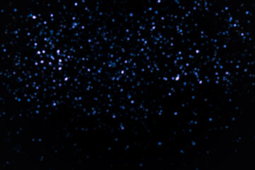 Bright and dark blue little stars blur bokeh on black background. Design element for overlay