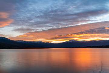 Atardecer en el lago con las montañas nevadas al fondo