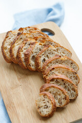 sourdough wheat bread on a wooden cutting board on a blue napkin, bread cut into pieces delicious fresh pastries