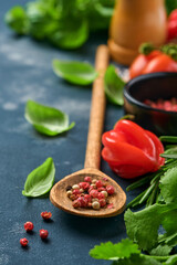 Food cooking background. Fresh rosemary, cilantro, basil, cherry tomatoes, peppers and olive oil, spices herbs and vegetables at black slate table. Food ingredients top view.
