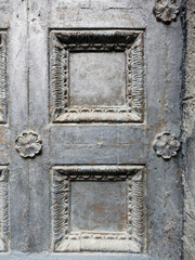 A wooden antique door close up covered in gray paint with a peeling edge