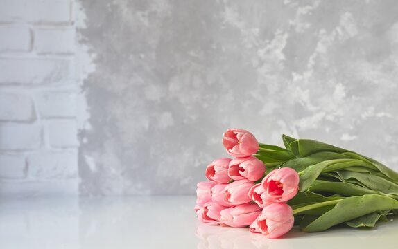 Close up image of beautiful pink tulip bouquet on white table, on bright background.