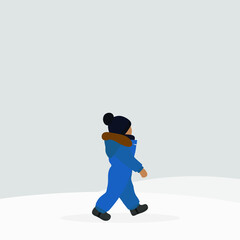 A small child in a hat and warm overalls walks in the snow