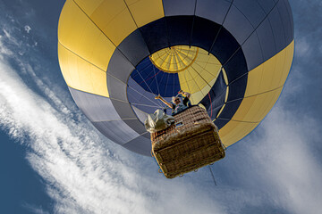 Pilotin winkt aus Korb des entschwebendem Heißluftballon - obrazy, fototapety, plakaty