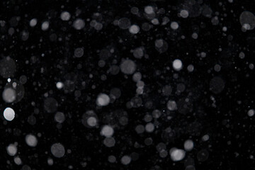 Falling snow out of focus on the black background. Snowfall for use as a texture layer in your project