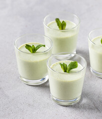 Obraz na płótnie Canvas Italian dessert Panna Cotta green mint in a glass on a light gray background