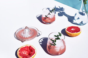 Summer grapefruit cocktail. Fresh healthy grapefruit beverage with herbs on sunlight with hard shadows. Creative drink on blue pastel background.