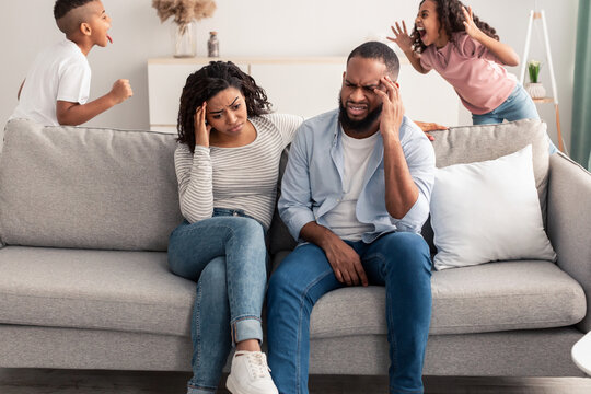 Noisy black children having fun near their tired parents