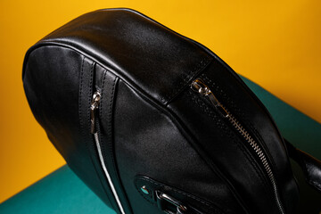 Naklejka premium A black leather bag, on a yellow background in a minimalist style, flower decor.