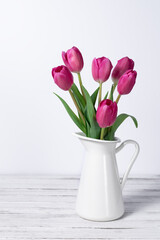 pink tulips in a jug on white background