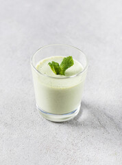 Vegan dessert creamy jelly green mint in a glass on a light gray background