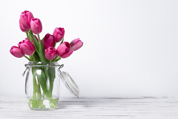 pink tulip flowers in a jug on white background