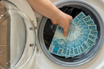 Brazilian money, the concept of money laundering from illegal activities. The man puts a large...