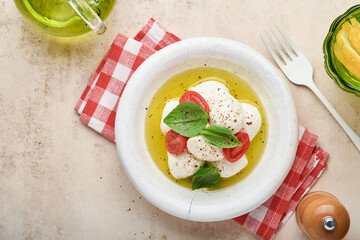 Caprese salad. Mozzarella cheese with basil and cherry tomato in white ceramic plate and tomato cherry on slate stone table background, copy space. Mock up.