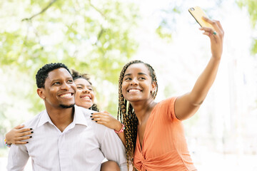 Family taking a selfie with a mobile phone at the park.