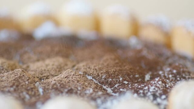 Delicious tiramisu cake on beige background. Tasty dessert top view, and powdered chocolate rotates in slow motion. Traditional Italian cuisine concept .