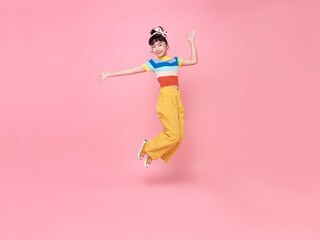 Asian child girl jumping up and wave her hands isolated on pink background.