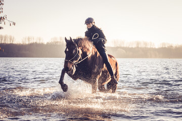 Reiterin mit Pferd im See