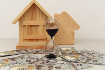 Wooden house and clock on dollar banknotes