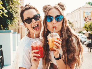 Two young beautiful smiling hipster female in trendy summer clothes. Carefree women posing...