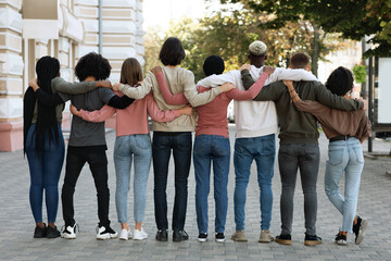 Back view of people hugging while standing on the street - obrazy, fototapety, plakaty