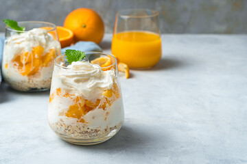 Orange dessert with cream and mint on a gray background. Whipped cream and fruit.